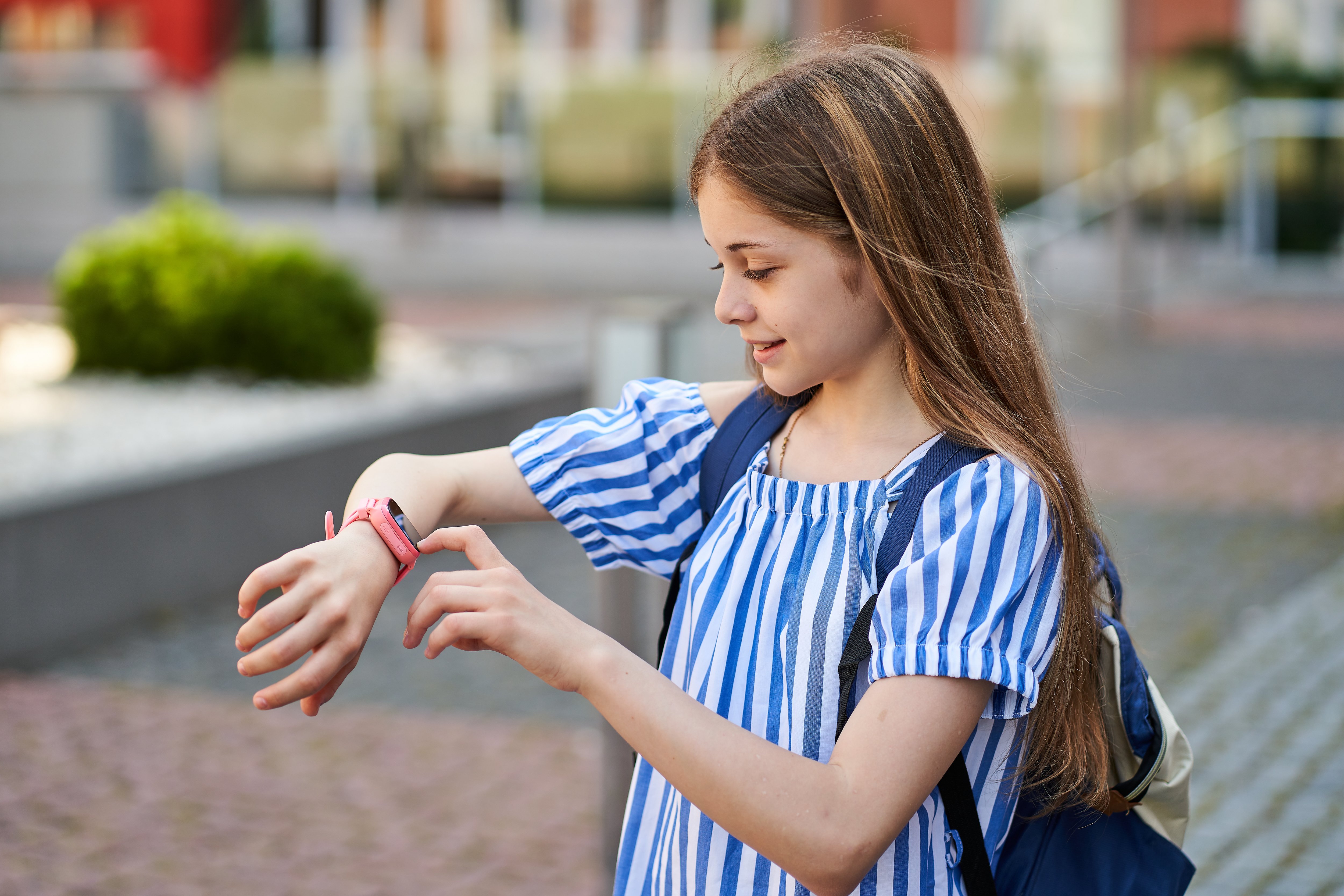 young-kid-girl-make-video-call-her-parents-with-her-pink-smartwatch-near-school